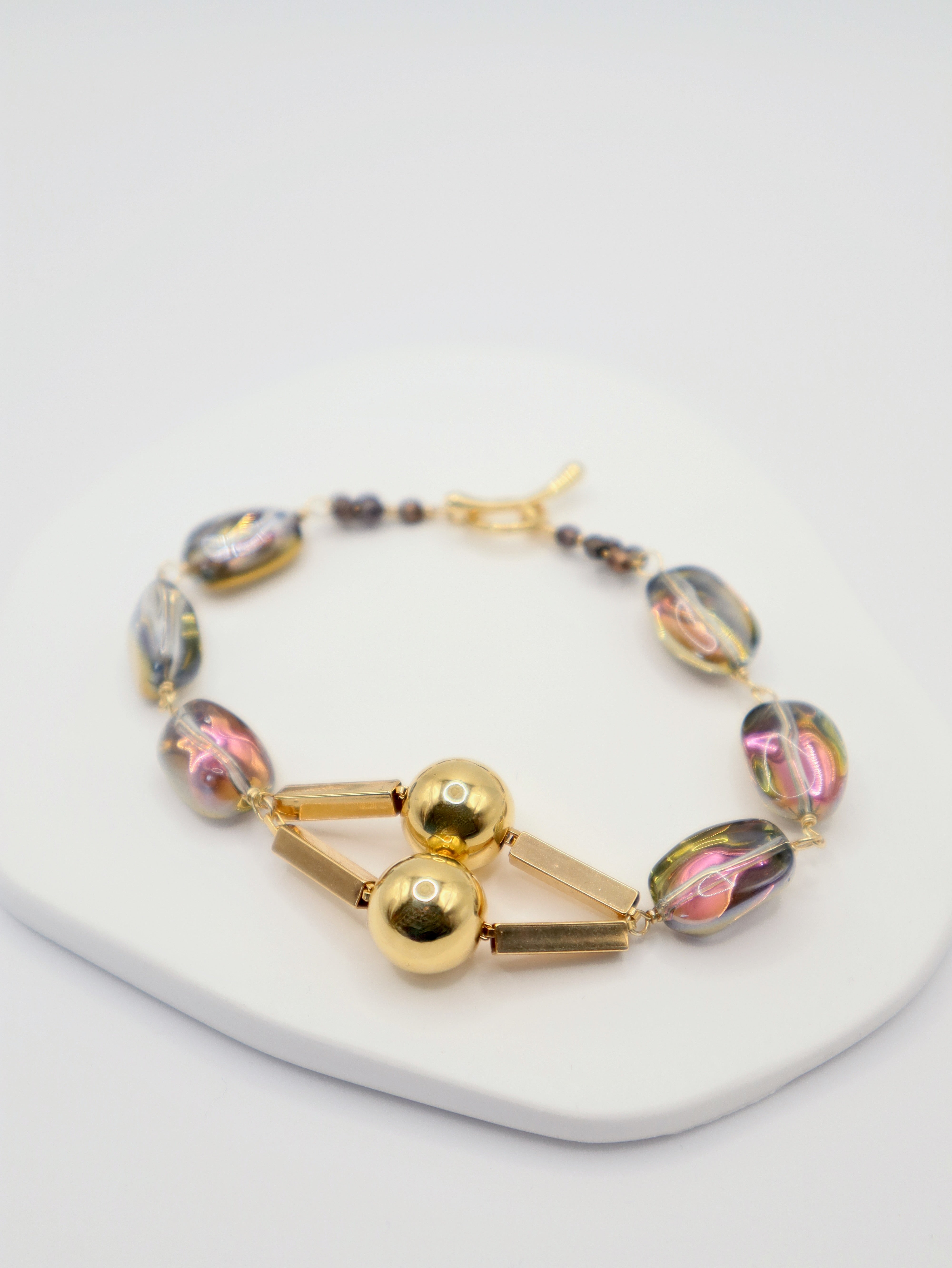 Bracelet with gold and multicoloured beads on a white background