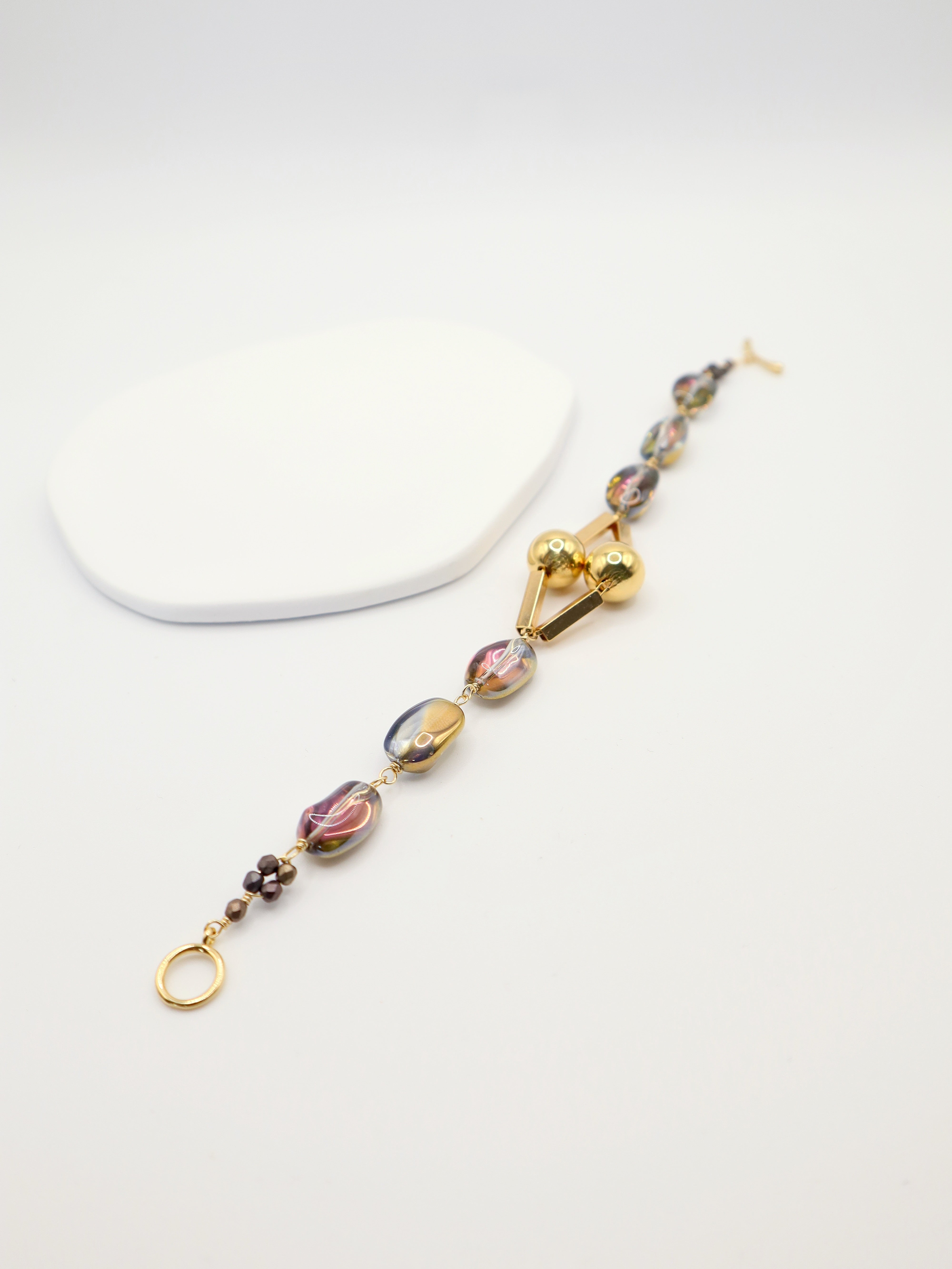Bracelet with multicoloured beads and gold clasp on a white background