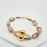 Bracelet with gold and multicoloured beads on a white background