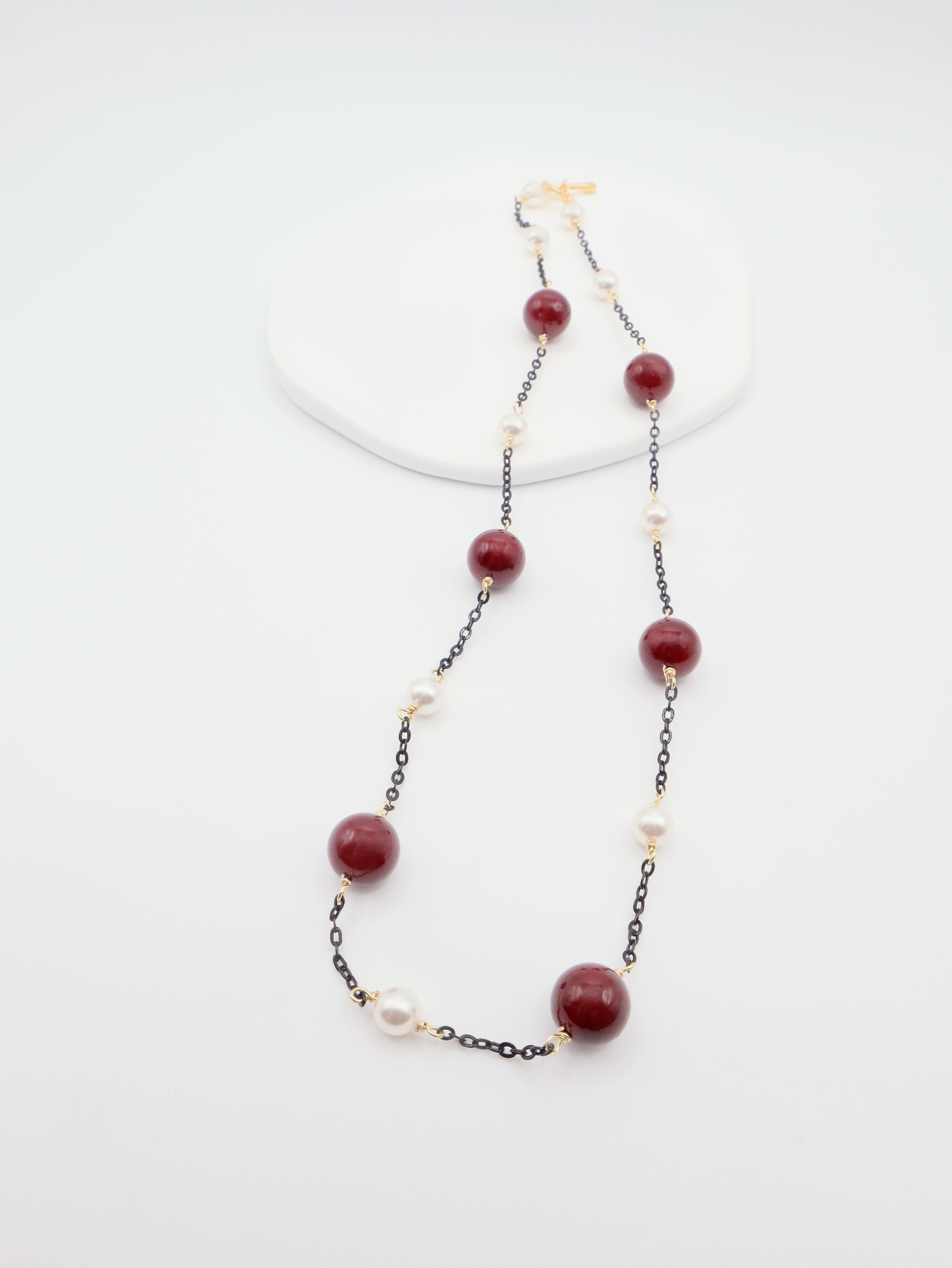 Necklace with burgundy beads and white pearls on a white background