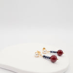 Pair of earrings with burgundy shell pearls and jet beads on a white surface