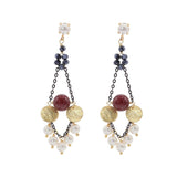Pair of earrings with white pearls, dark chain and gold discs on a white background