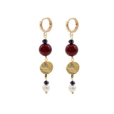 Pair of gold hoop earrings with burgundy shell pearls, gold discs , and pearl beads on a white background