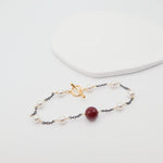 Delicate bracelet with burgundy shell and gold clasp on a white background