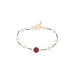 Bracelet with pearls and a red shell pearl on a white background