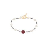 Bracelet with pearls and a red shell pearl on a white background