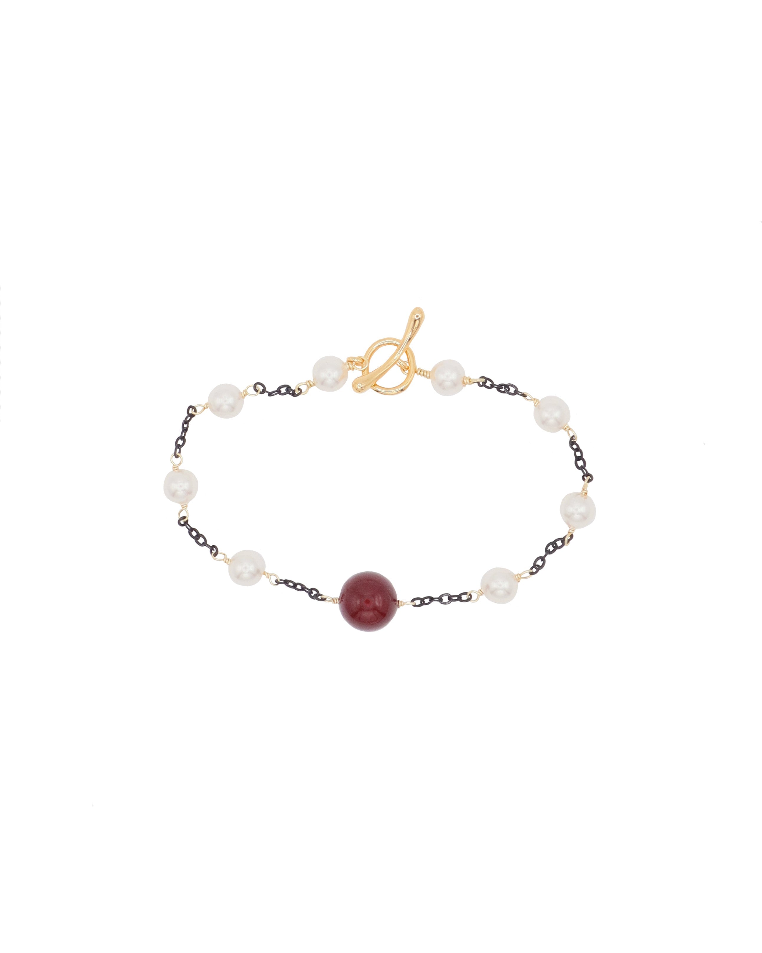 Bracelet with pearls and a red shell pearl on a white background