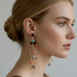 Woman wearing a pair of dangling earrings with a neutral background