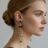 Woman wearing a pair of dangling earrings with a neutral background