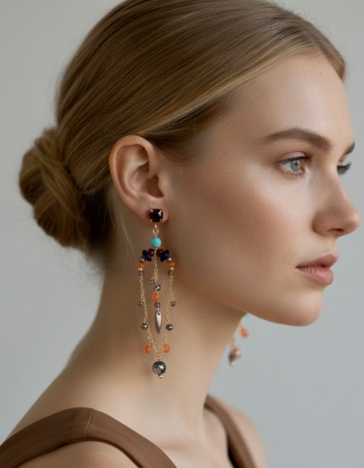 Woman wearing a pair of dangling earrings with a neutral background