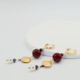 Earrings with gold, burgindy, and pearl beads on a white background