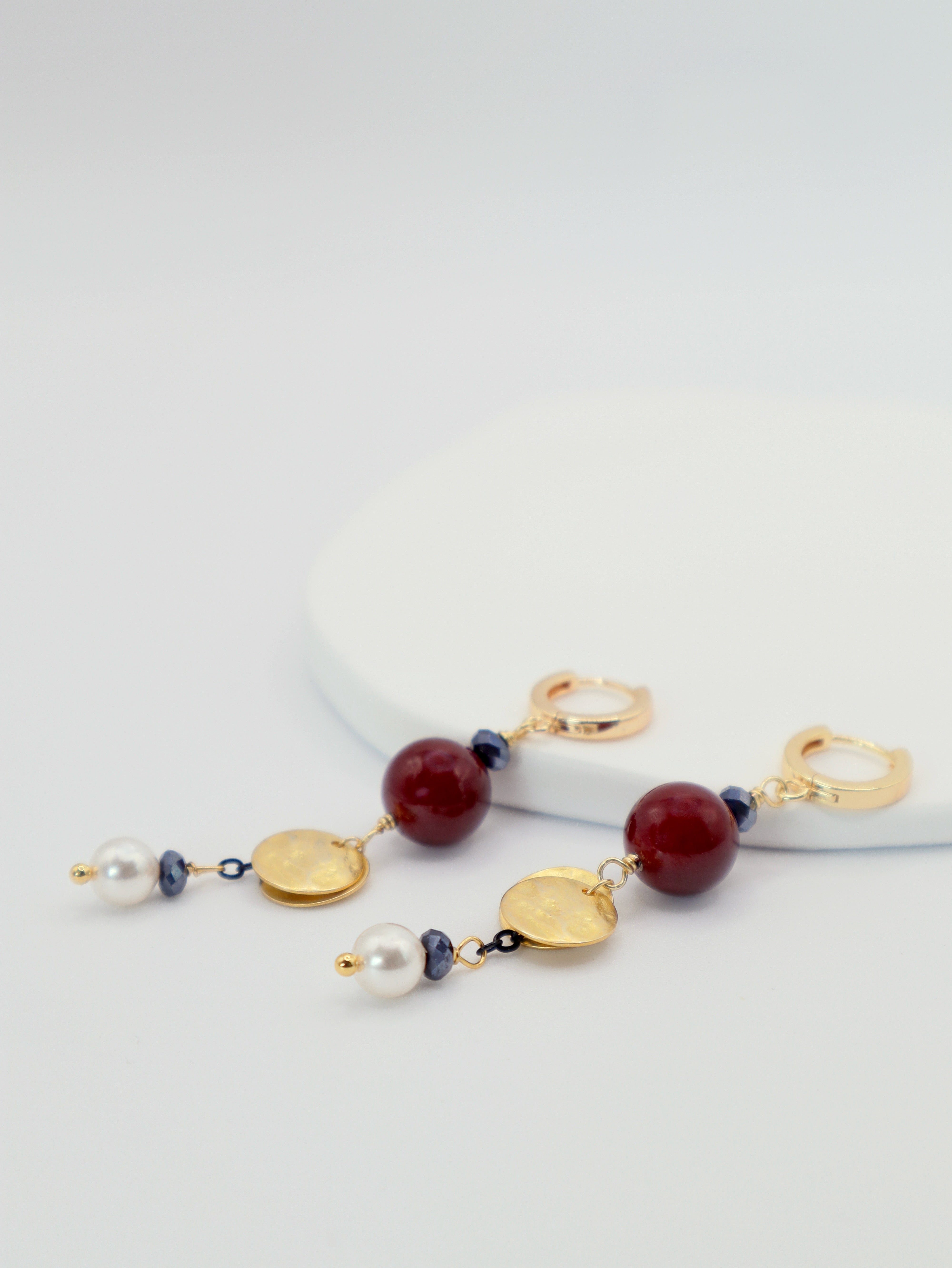 Earrings with gold, burgindy, and pearl beads on a white background