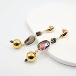 Gold and multicolored bead earrings on a white surface