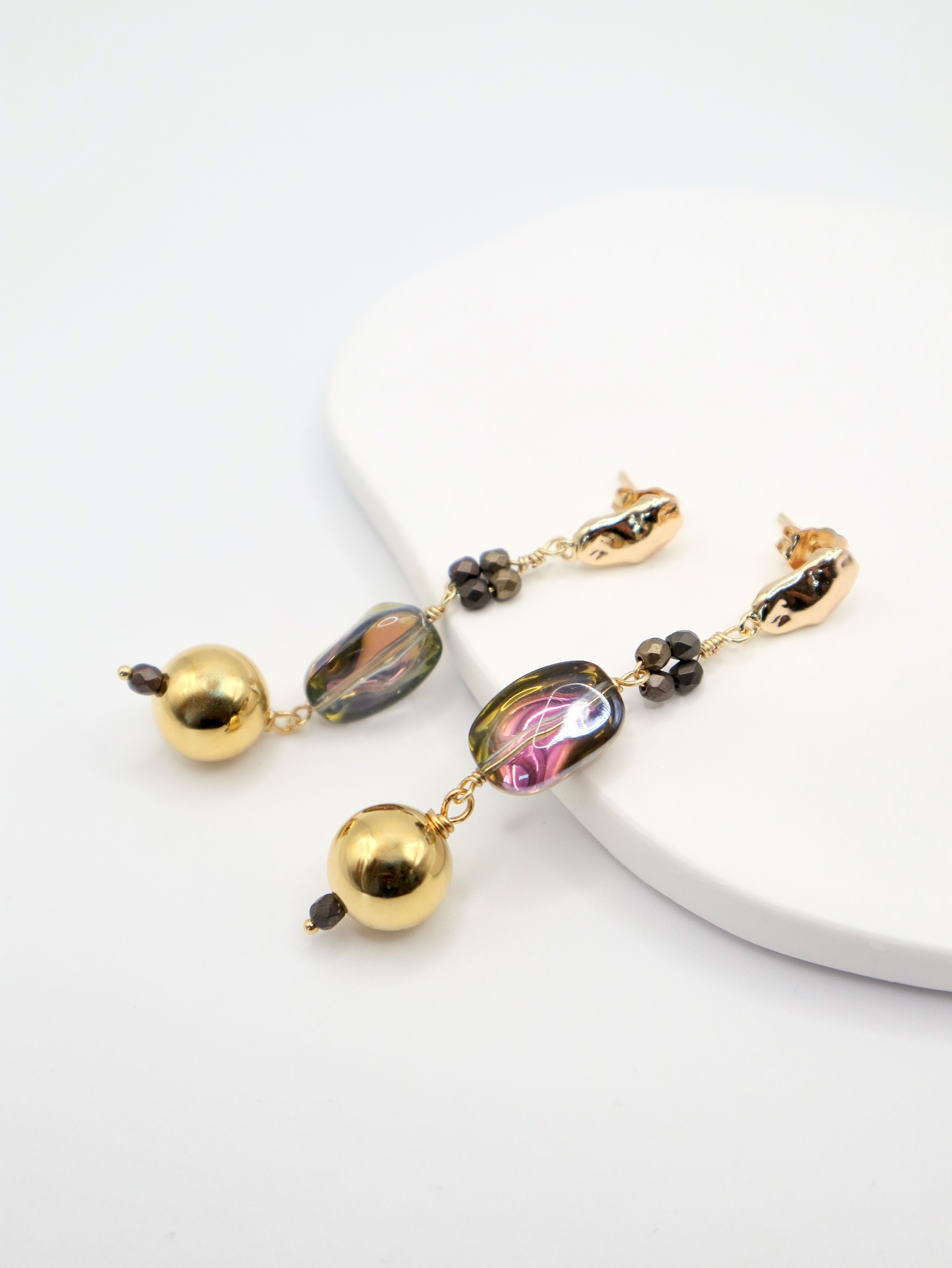 Gold and multicolored bead earrings on a white surface