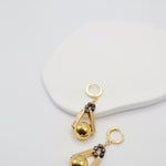 Gold earrings with bronze beads on a light gray background