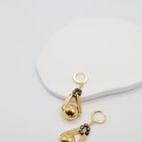 Gold earrings with bronze beads on a light gray background