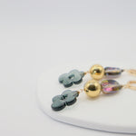 Pair of earrings with floral and round designs on a white surface