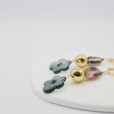 Pair of earrings with floral and round designs on a white surface