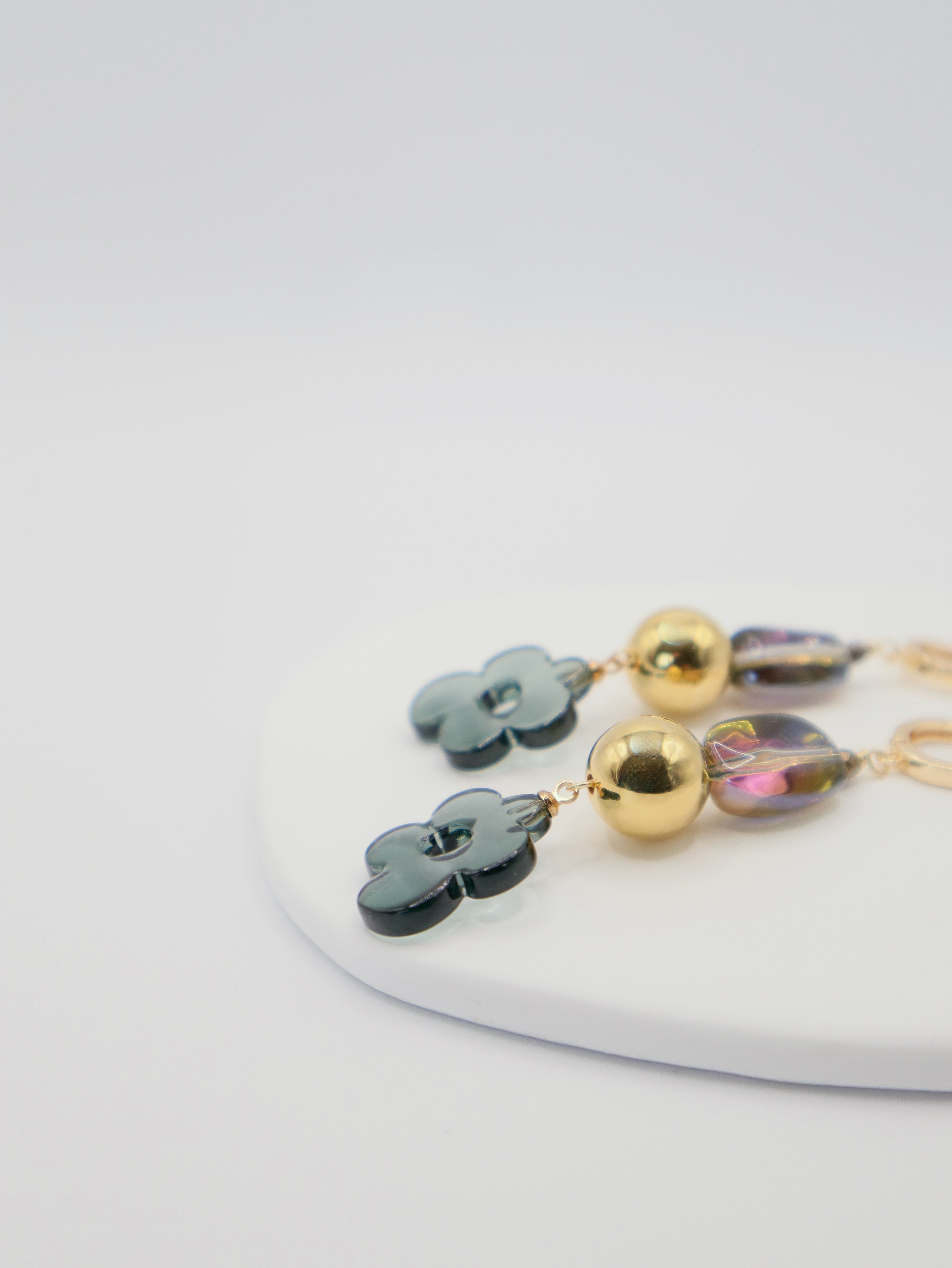 Pair of earrings with floral and round designs on a white surface