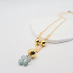 Necklace with green resin floral pendant and gold elements on a white background