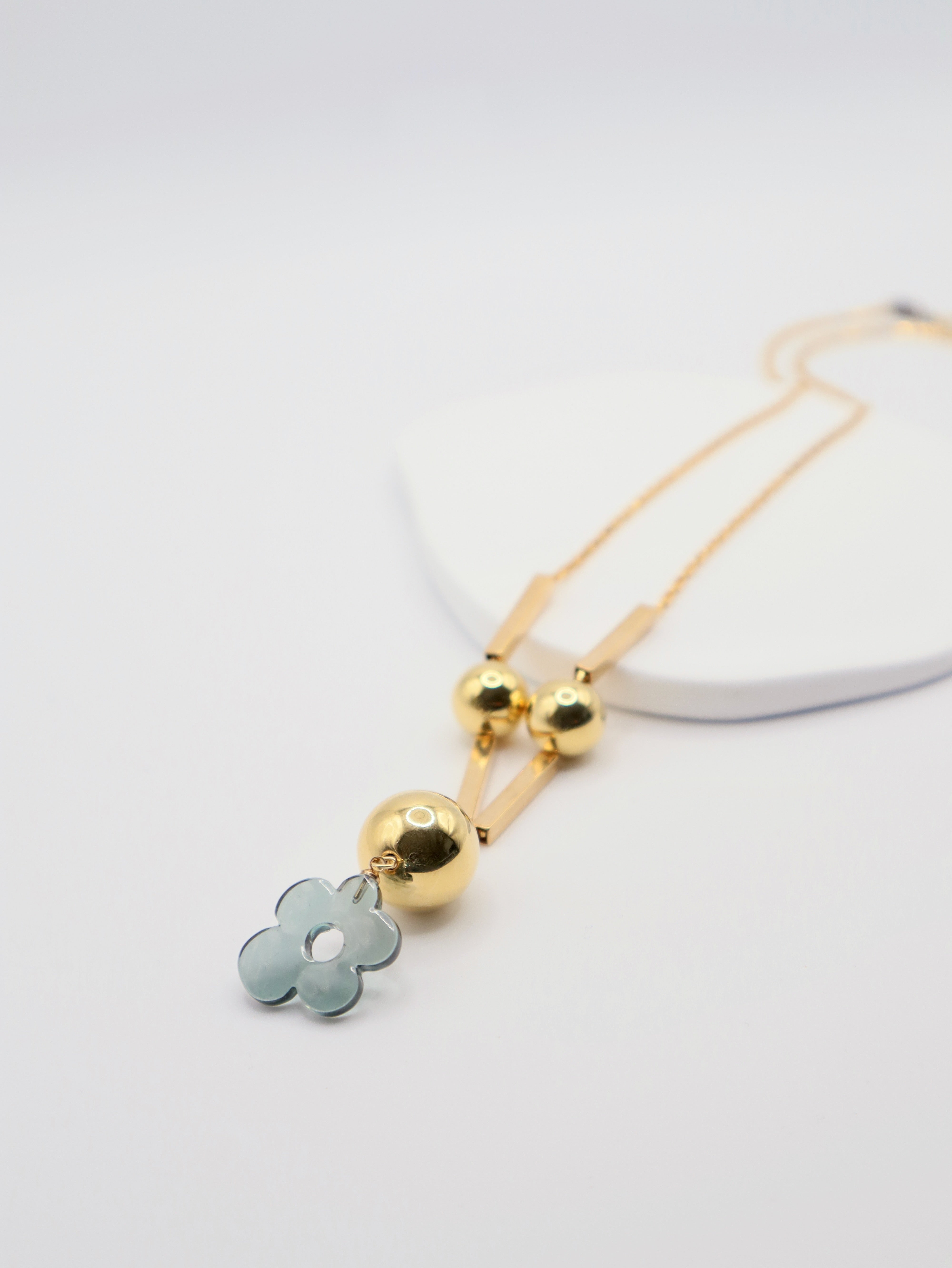 Necklace with green resin floral pendant and gold elements on a white background