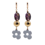 Pair of earrings with gold beads and flower-shaped charms on a white background