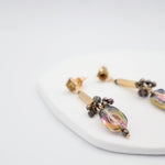 Pair of earrings with glass beads and gold bar on a white surface
