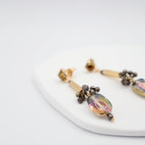Pair of earrings with glass beads and gold bar on a white surface