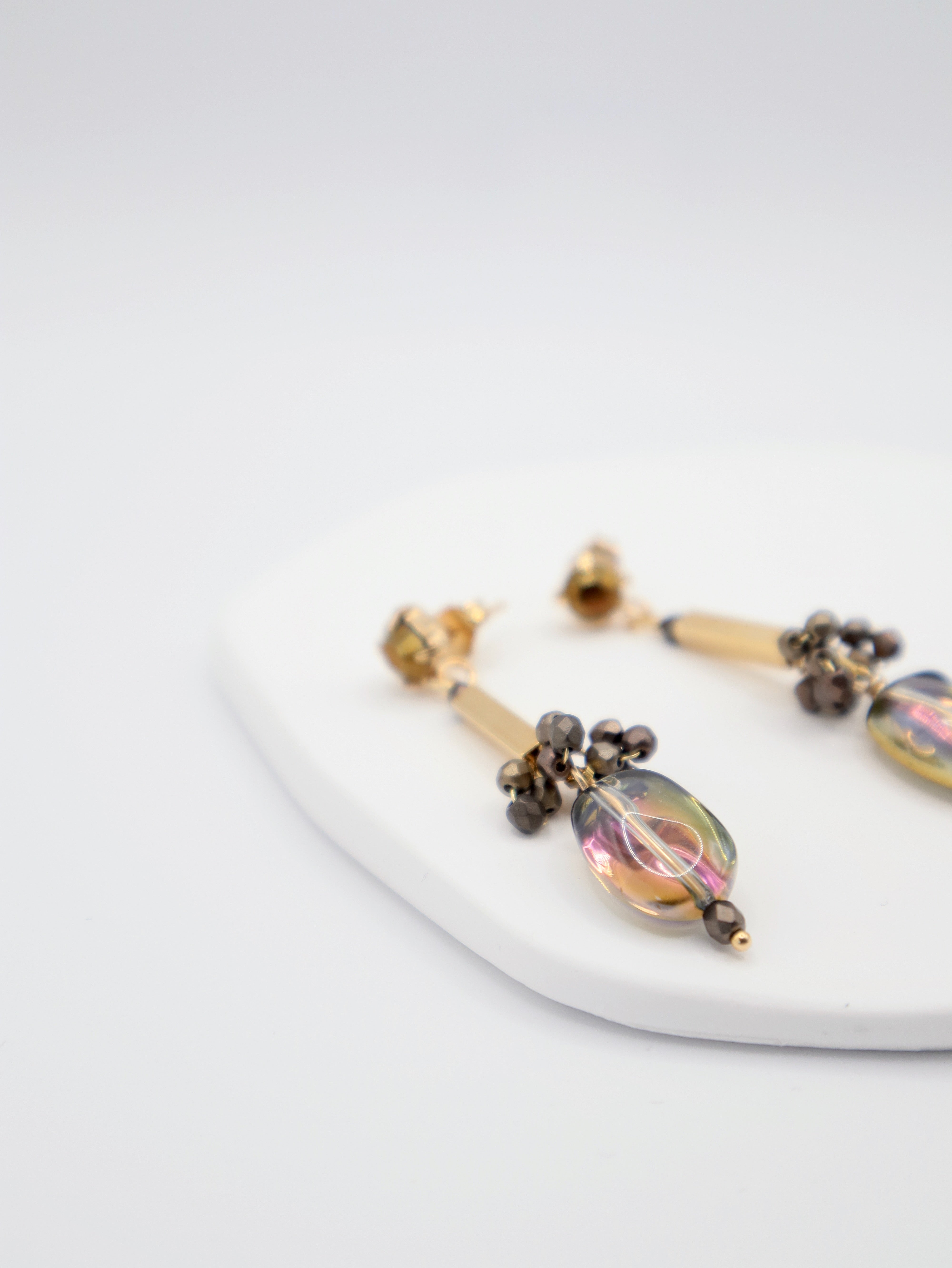 Pair of earrings with glass beads and gold bar on a white surface
