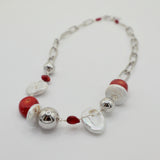 Necklace with red coral, freshwater pearls and silver beads on a white background