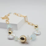 Necklace with gold spheres, freshwater pearls and aquamarine beads on a white background