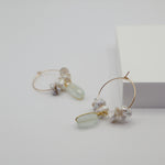 Gold hoop earrings with pearls and aquamarine stones on a light gray background