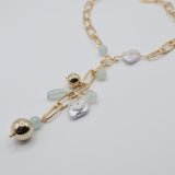 Gold necklace with freshwater pearl coins  and gold sphere beads on a light grey background