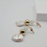 Pair of earrings with pearl coins, gold spheres and aquamarine beads on a light grey background