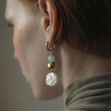 Close-up of an earring with pearls and gold elements on a neutral background