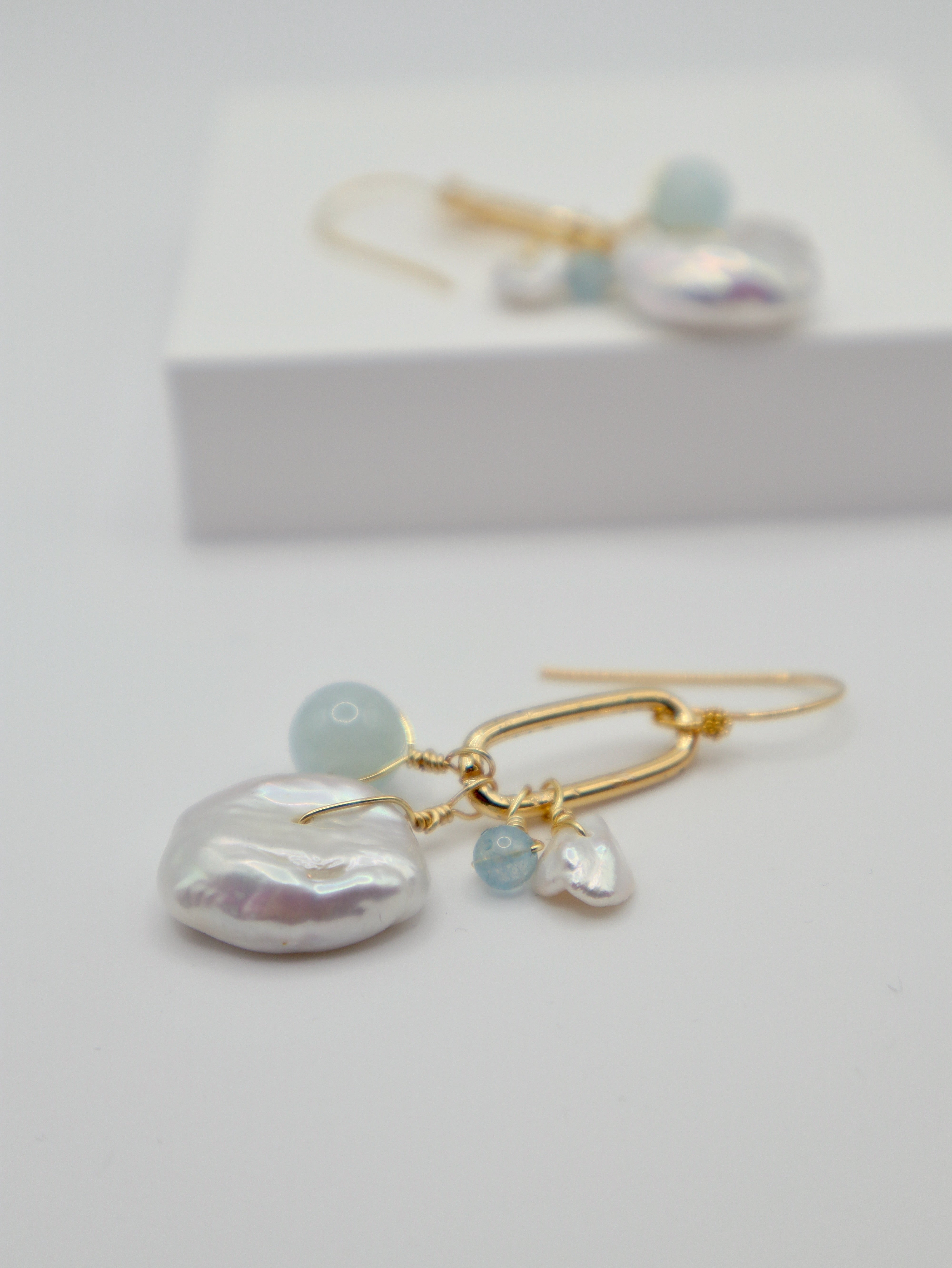 Pearl and aquamarine earrings on a white background