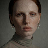 Woman wearing mini hoop earrings with freshwater pearl flakes and aquamarine stones