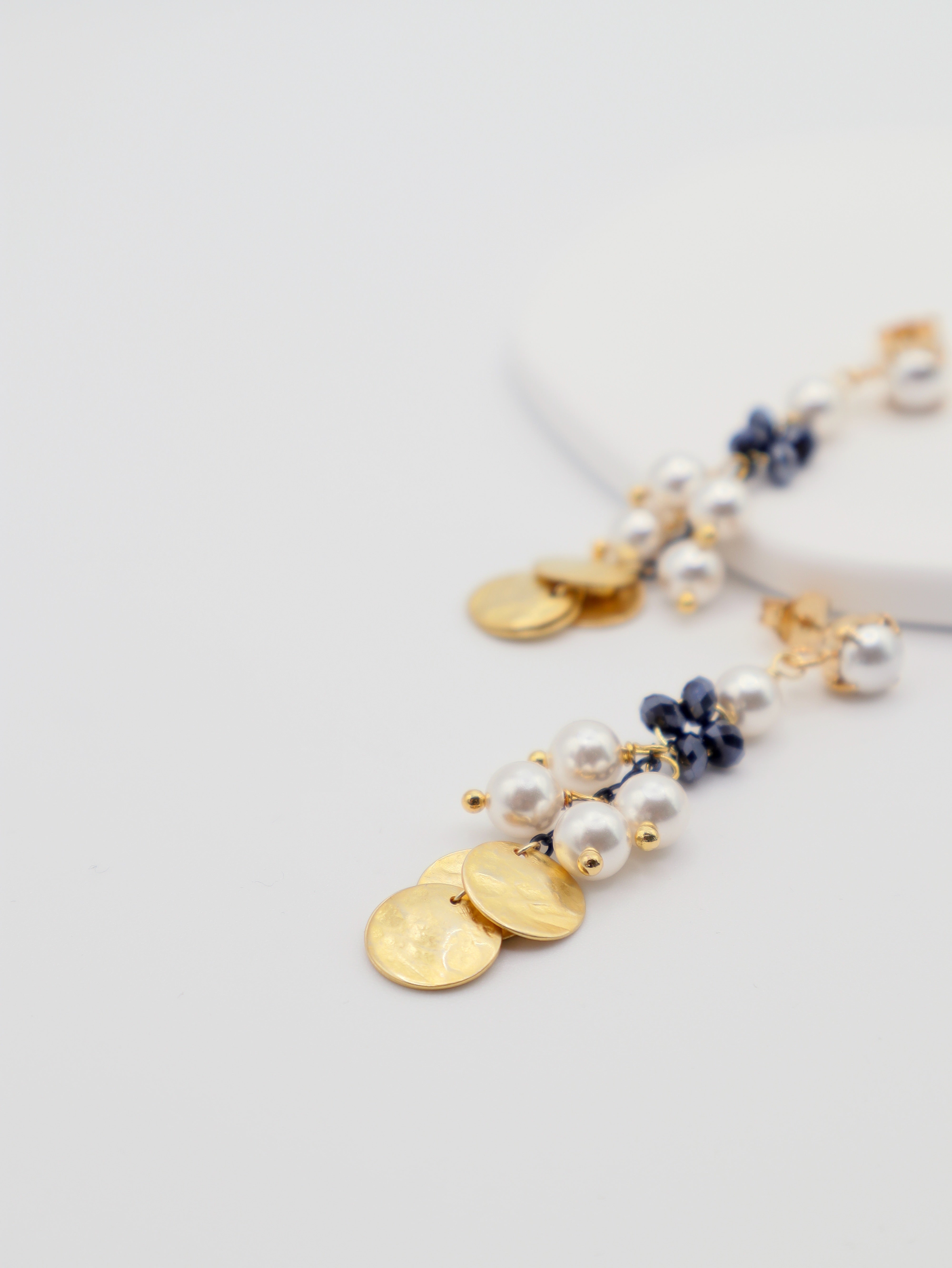 Delicate gold and pearl earrings on a light gray background