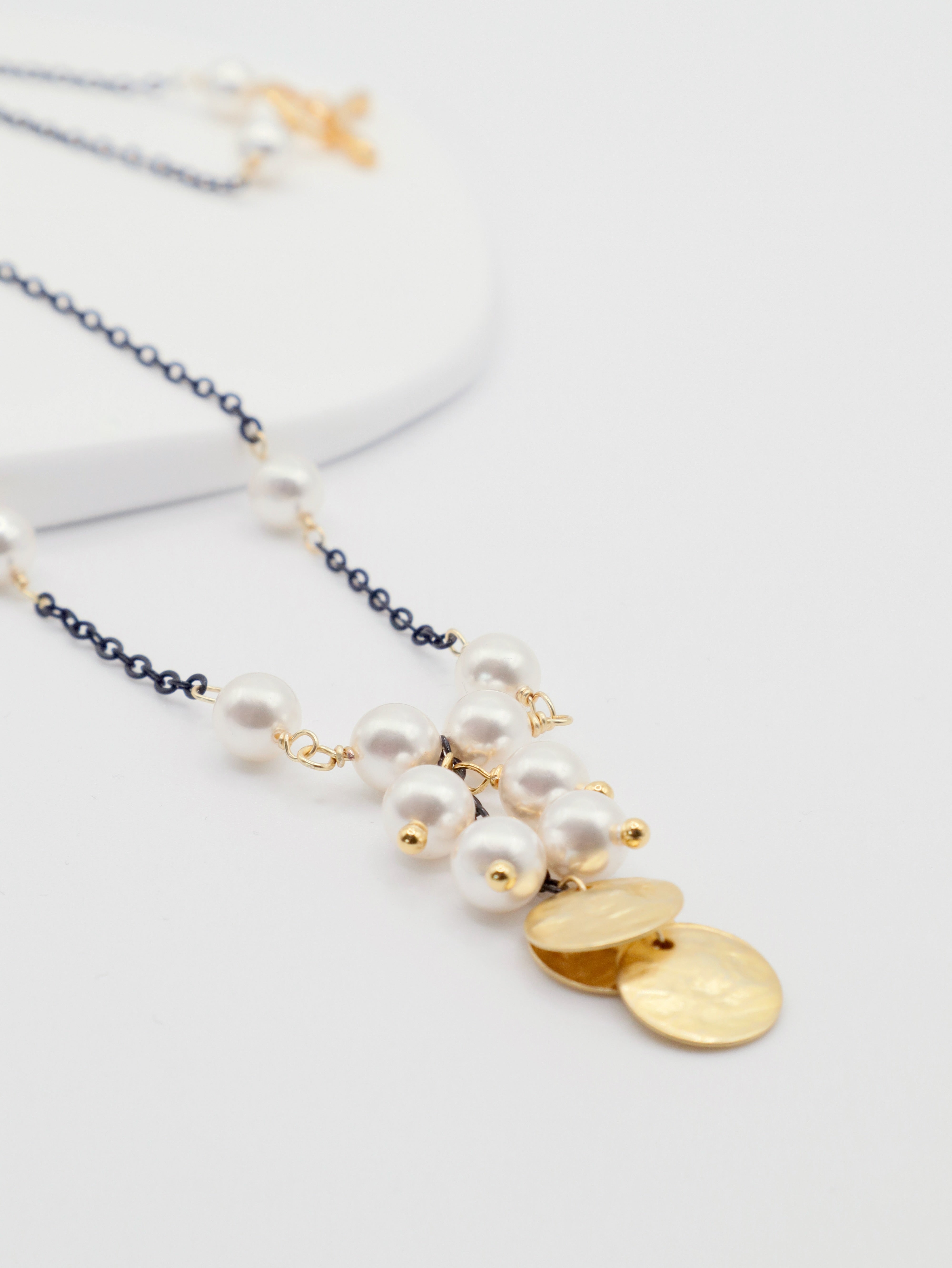 Necklace with pearls and gold pendants on a white background