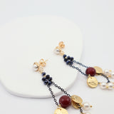 Statement earrings featuring pearls, burgundy beads and gold discs on black chain