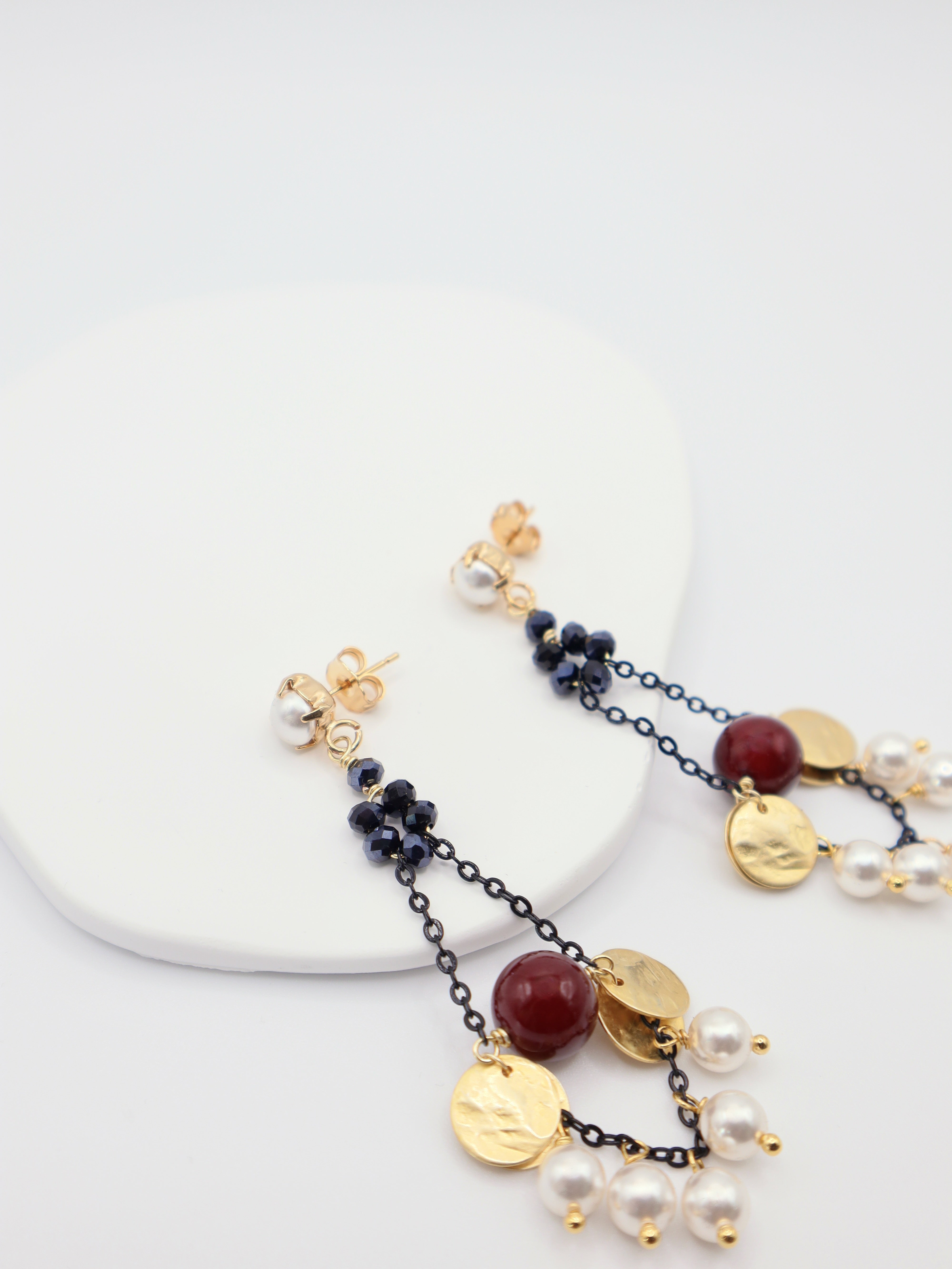 Statement earrings featuring pearls, burgundy beads and gold discs on black chain
