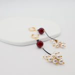 Pair of earrings with pearls and burgundy beads on a white background