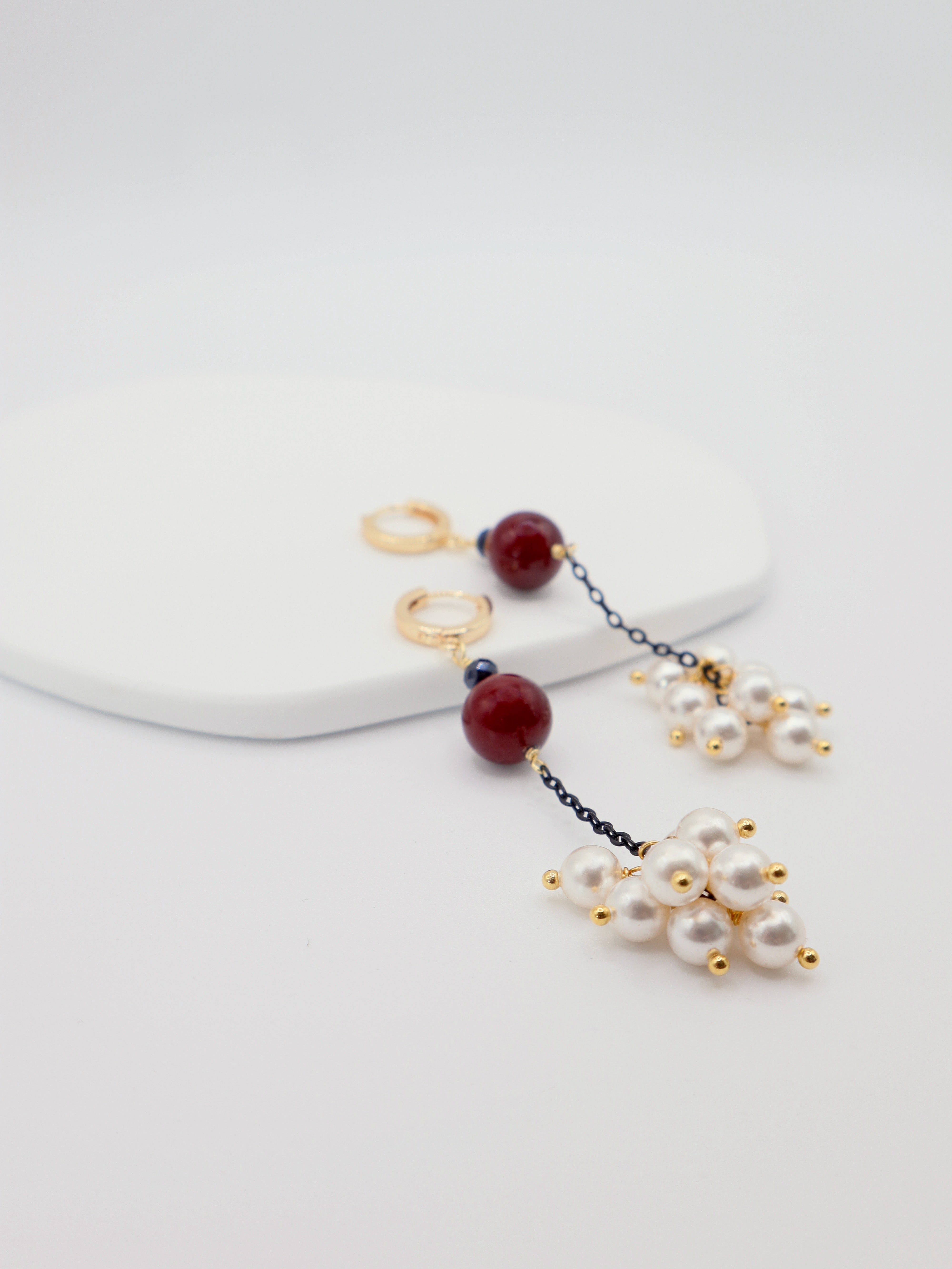 Pair of earrings with pearls and burgundy beads on a white background