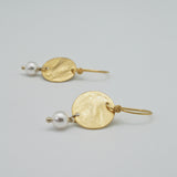 hammered gold disc earrings with white pearl drop lying flat by vivien walsh